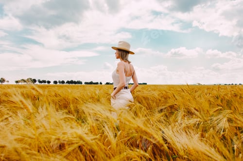 Preview: Woman with a blond hair and white hat on golden wheat field