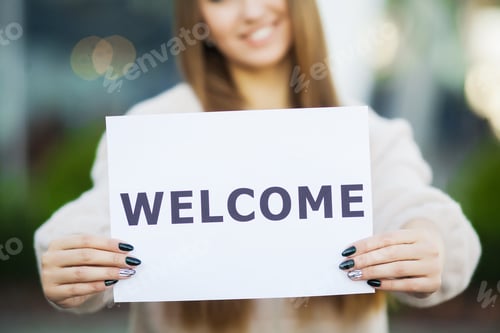 Preview: Businesswoman with long Hair Holding a sign Board with a Welcome has Airport Background