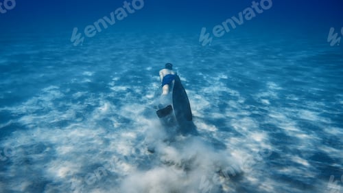 Preview: Boy snorkels with fins on the seabed raising sand smoke in the ocean