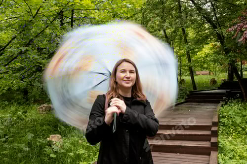 Preview: young woman walking in the park in the summer in rainy weather