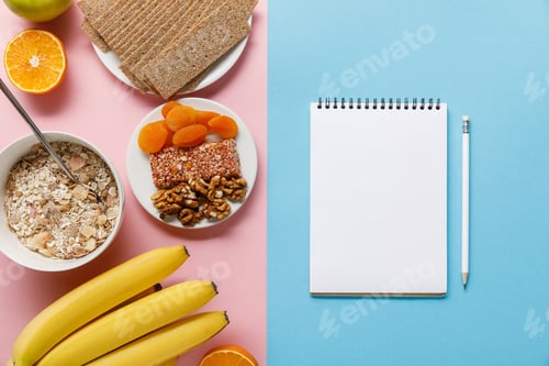 Preview: top view of fresh fruits, crispbread and breakfast cereal on pink and blank notebook on blue