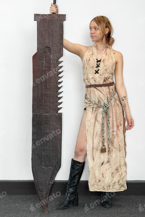 Preview: Female cosplayer in a horror outfit posing with a large blade sword on a white background