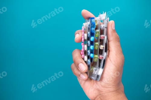 Preview: hand holding blister packs on green background