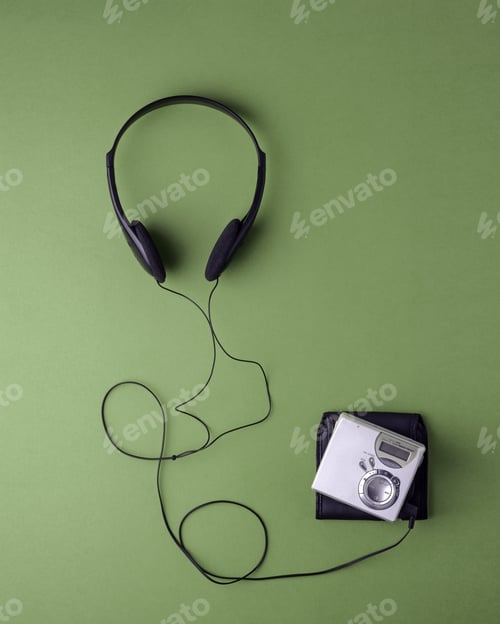 Preview: Minimalistic composition of black headphones and silver minidisc player on green background