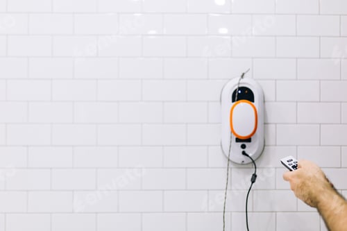 Preview: Man washes the white tiles on the walls in the bathroom with a gadget - a window cleaner