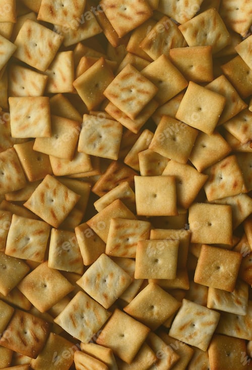 Preview: A lot of small cookies are square shaped. A pattern of a yellow salt cracker. Background im