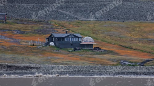 Preview: A remote cabin nestled along the Svalbard coastline surrounded by vibrant tundra landscape