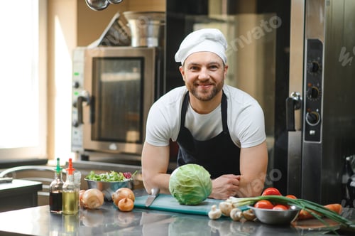Preview: Portrait of a smiling male chef with cooked food standing in the kitchen