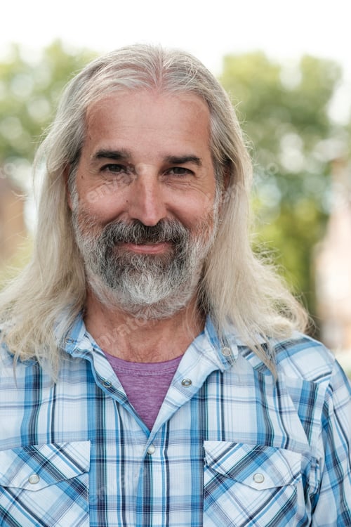 Preview: Portrait of smiling senior man with long gray hair and beard outdoors