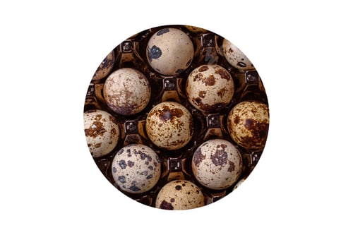 Vista previa: Raw quail eggs in a plastic box on a dark concrete background