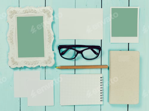 Preview: Stylish workspace arrangement with stationery and empty frames on a wooden table