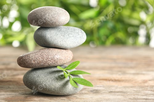 Preview: Spa stones and bamboo leaves on table against blurred background. Space for text