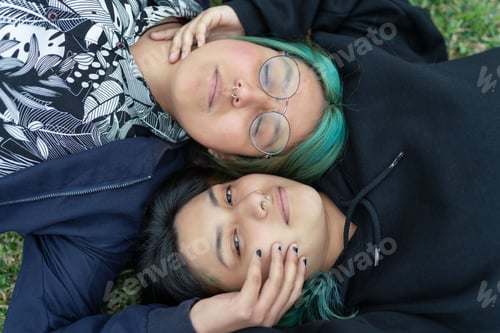 Preview: High angle view of a lesbian couple lying on the grass