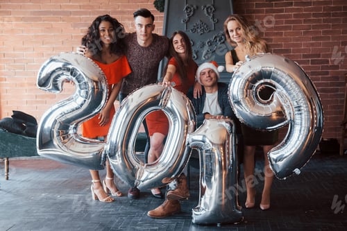 Visualização: Lindos jovens amigos, se divertindo na véspera de Ano Novo, com números para 2019