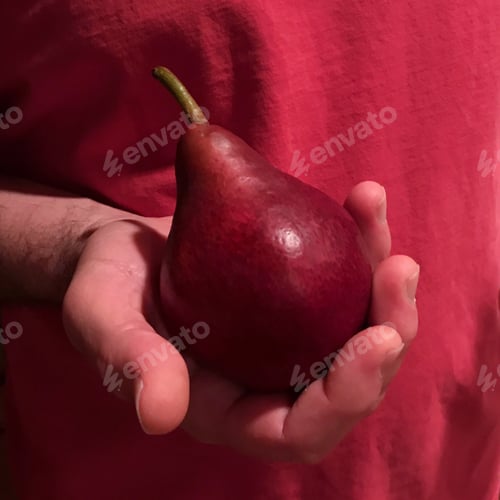Preview: Man holding red pear in front of his red shirt