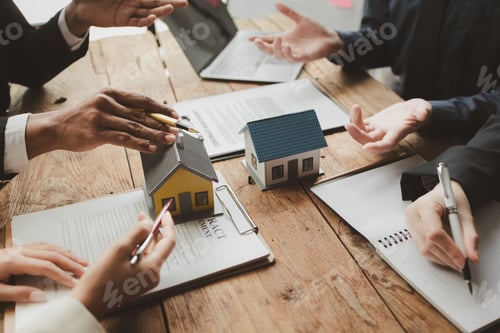 Real Estate Meeting with House Models and Contracts