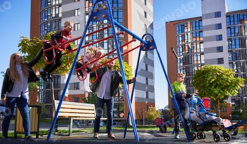 Preview: Happy family - father, mother and children having fun together on playground.