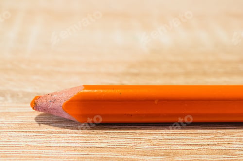 Preview: Closeup shot of an orange drawing pencil on a wooden surface