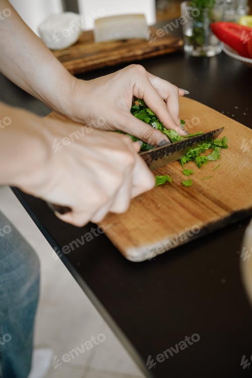 Preview: Unrecognizable woman chopping cilantro on cutting board