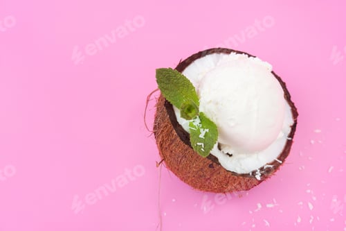 Preview: Vanilla ice cream balls in fresh coconut halves, decorated with mint leaves on a pink background