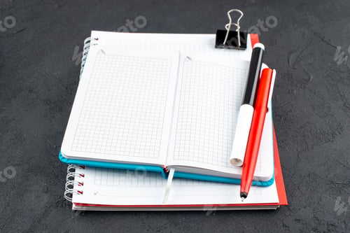 Preview: bottom view office stuffs notepads black marker red pen binder clip on dark background