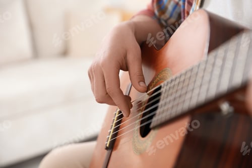 Preview: Man playing guitar at home, focus on hand. Space for text