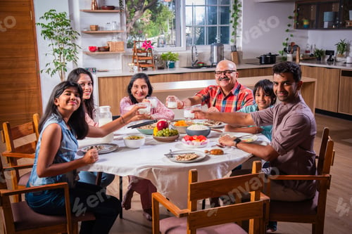 Preview: Indian family having lunch at home on dining table with grandparents, parents and kids