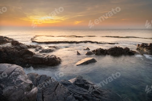 Preview: Long exposure seascape of rocky coastal during sunsetting with golden skyline