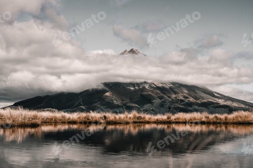 Preview: calm lake surrounded by fine soft plants near the top of the big mountain peeking above the low