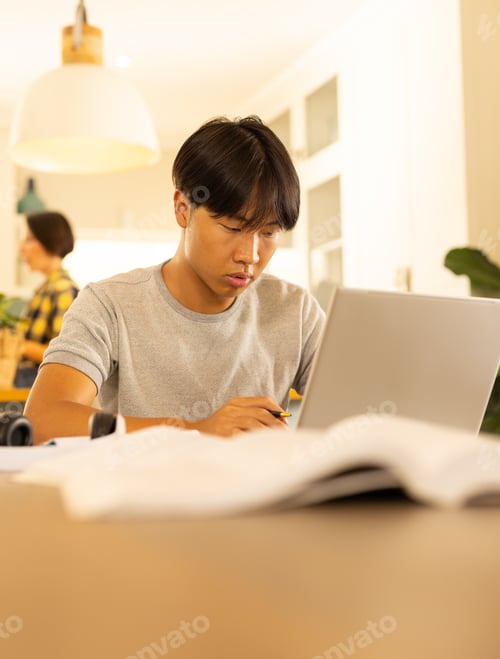 Preview: Using laptop, young man focusing on work at home office desk
