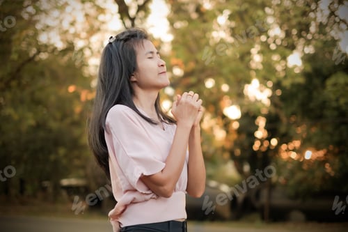 Preview: Woman standing with eyes closed on blur bokeh and tree on sun set.