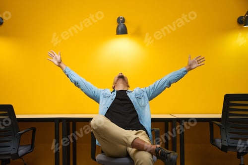 Vista previa: Happy man sitting on chair and rising hands up
