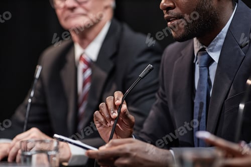 Preview: Hand of Black Man Adjusting Mic Sitting at Table while Speaking at Political Committee Meeting