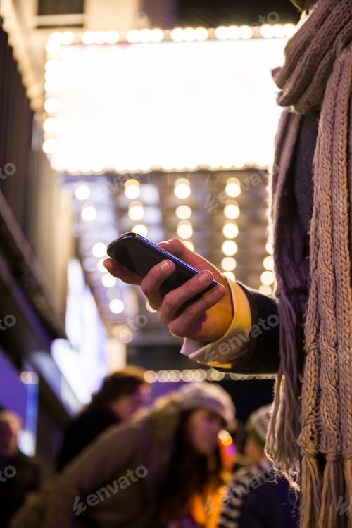 Preview: Hand of a man using his cell phone in the city at night