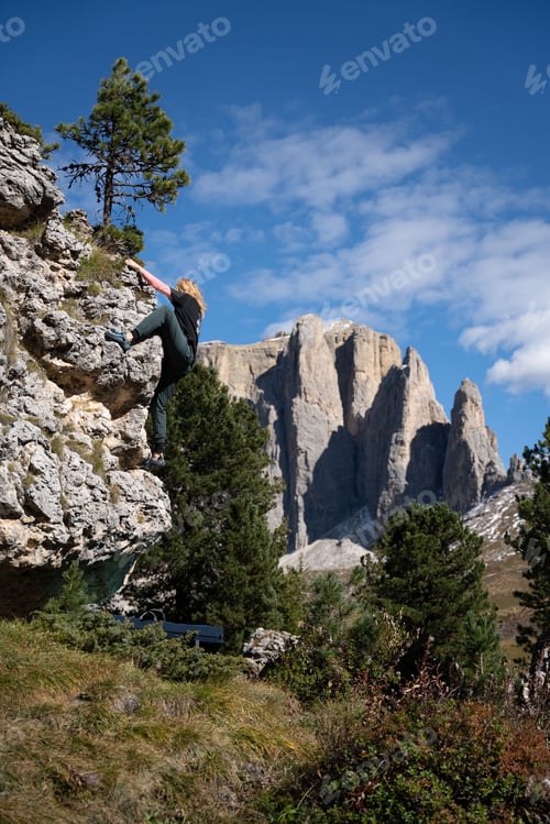 Preview: Closeup of a young, attractive blonde woman climbing bouldering in the Dolomites, Italy