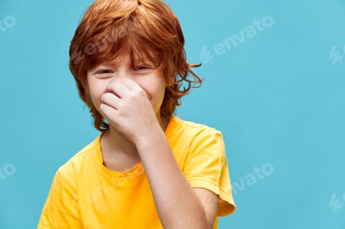 Preview: Laughing boy with red hair covers his face with his hand