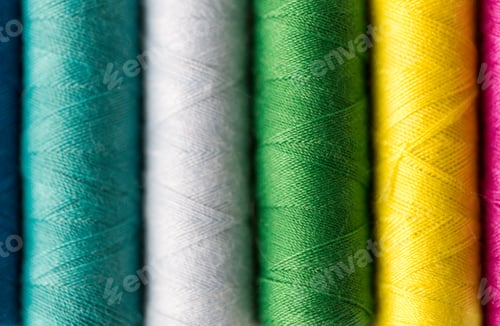 Preview: row of colorful thread spools on table