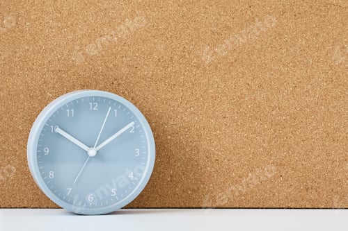 Preview: Gray alarm clock and corc board on a white table