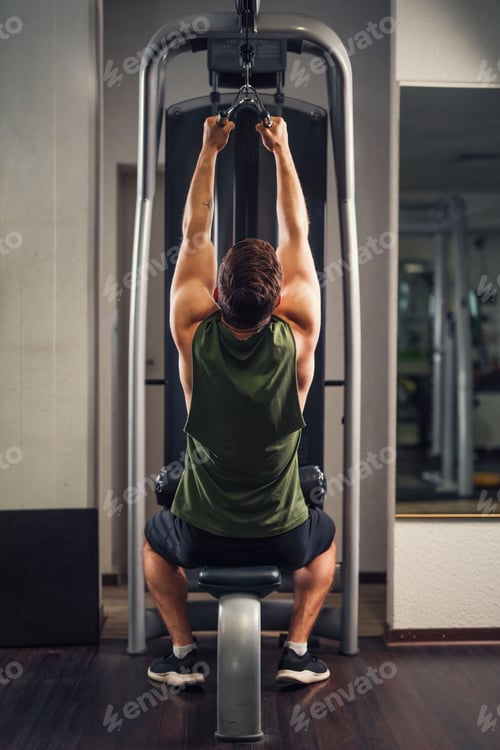 Preview: Back view of male doing exercise at lat pull machine with rope handle