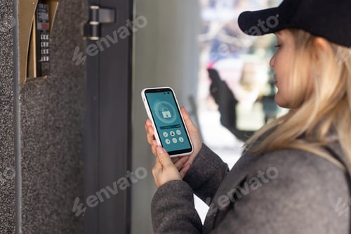 Preview: Female hand holding black mobile smart phone with smart home application on the screen. Blurred
