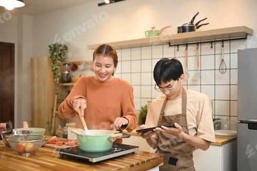 Preview: Young couple enjoying a lighthearted moment while preparing a meal together in kitchen