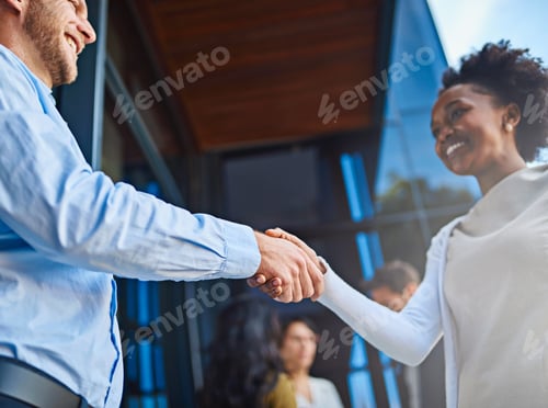 Preview: Cropped shot of two businesspeople shaking hands with their coworkers in the background
