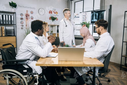 Preview: Mature doctor talking about x ray scan to diverse colleagues