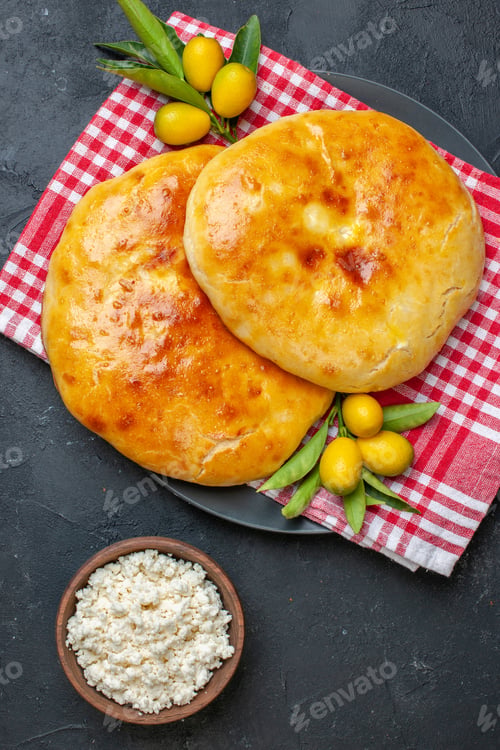 Preview: Vertical view of delicous fresh baked pastries kumquats with stem on red stripped towel and cheese