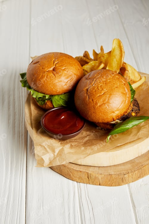 Preview: Hamburgers and french fries with ketchup served on craft paper on white table
