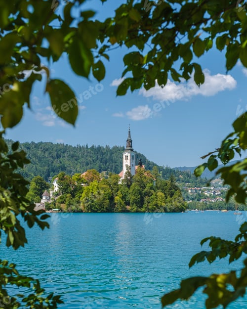 Preview: A serene view of Lake Bled, Slovenia, with its iconic island church framed by lush foliage