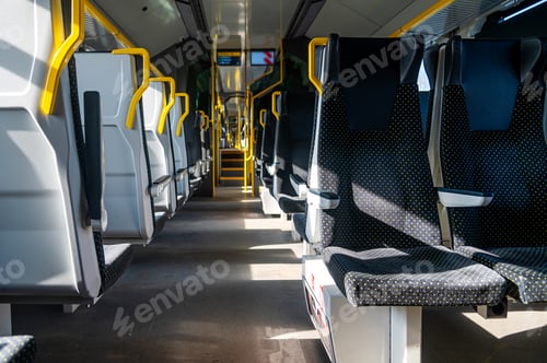 Vista previa: Empty train interior with yellow handrails for passengers during daytime travel