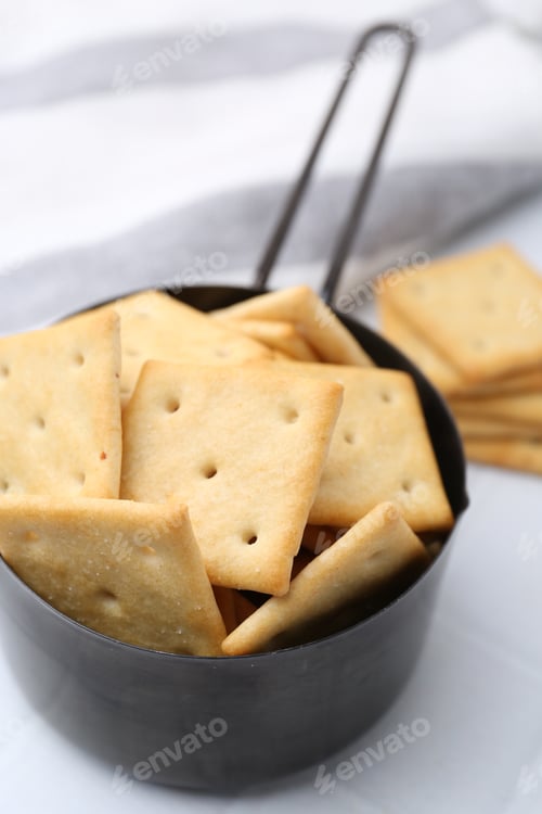 Preview: Tasty salty crackers on white tiled table, closeup