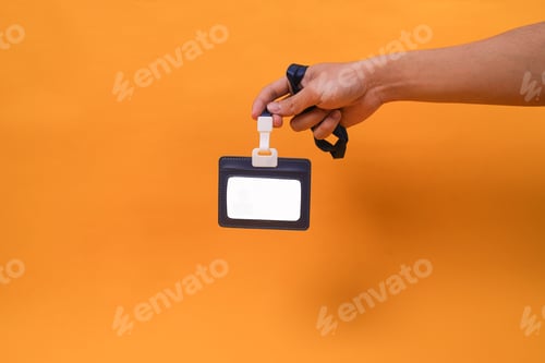 Preview: Studio Shot Hand Holding Blank ID Badge With Lanyard Against Yellow Background