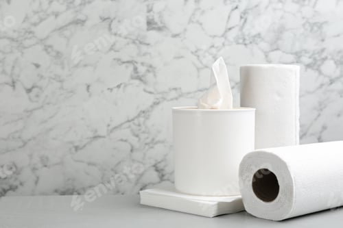 Preview: Clean napkins, box with tissues and rolls of paper towels on light table, space for text